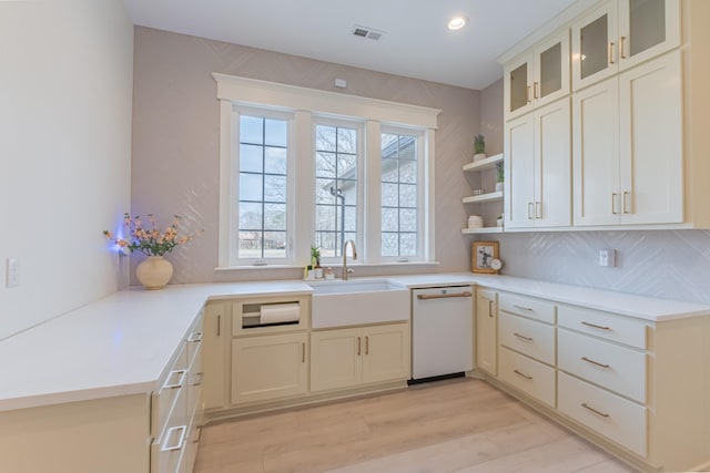 kitchen featuring dishwasher, sink, light hardwood / wood-style flooring, and backsplash