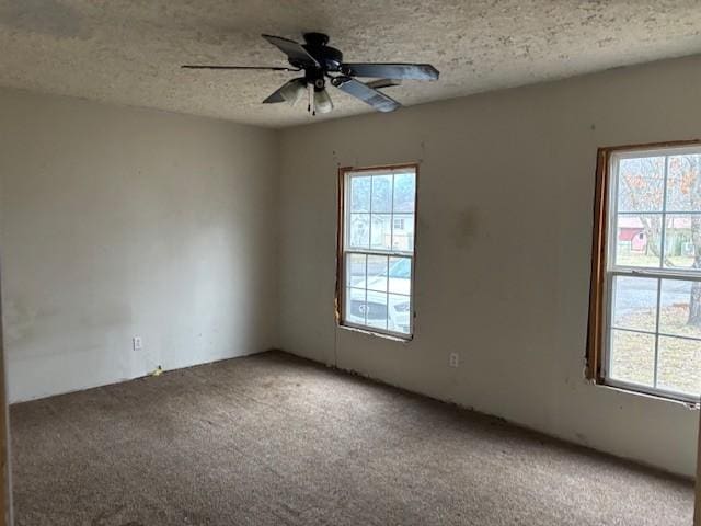 carpeted empty room featuring ceiling fan, a healthy amount of sunlight, and a textured ceiling