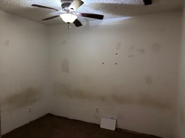 empty room with ceiling fan and a textured ceiling