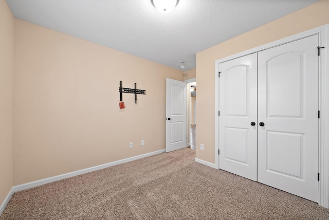 unfurnished bedroom featuring light carpet, a closet, and a textured ceiling