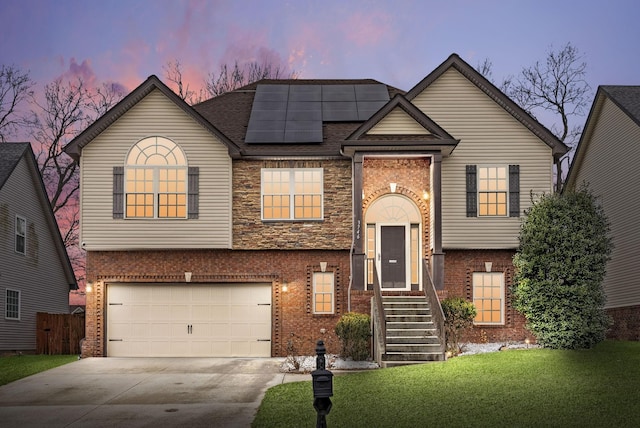 raised ranch with a yard, a garage, and solar panels