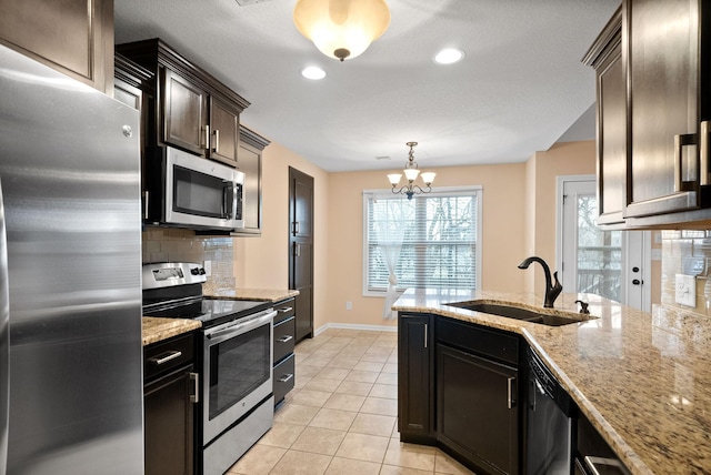 kitchen with light tile patterned flooring, appliances with stainless steel finishes, sink, backsplash, and hanging light fixtures