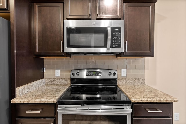 kitchen with tasteful backsplash, light stone countertops, appliances with stainless steel finishes, and dark brown cabinets