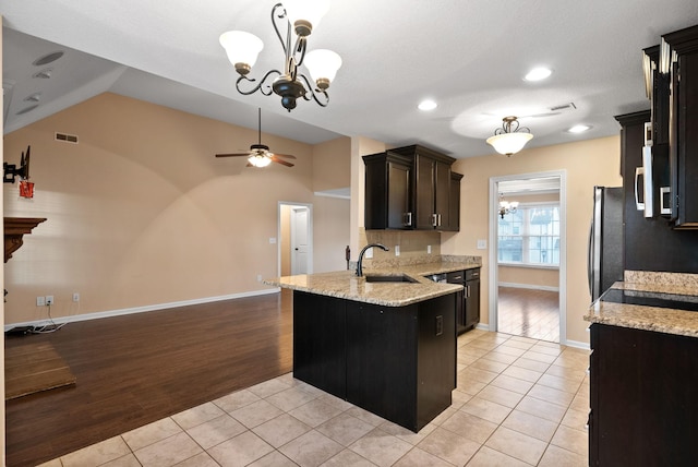 kitchen with ceiling fan with notable chandelier, sink, hanging light fixtures, light tile patterned floors, and light stone countertops