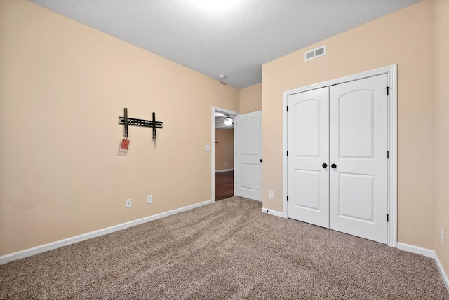 unfurnished bedroom with carpet, a textured ceiling, and a closet