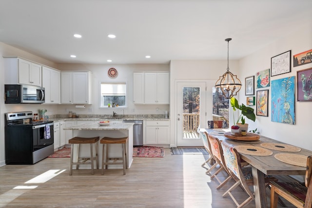 kitchen featuring decorative light fixtures, stainless steel appliances, white cabinets, and a kitchen island