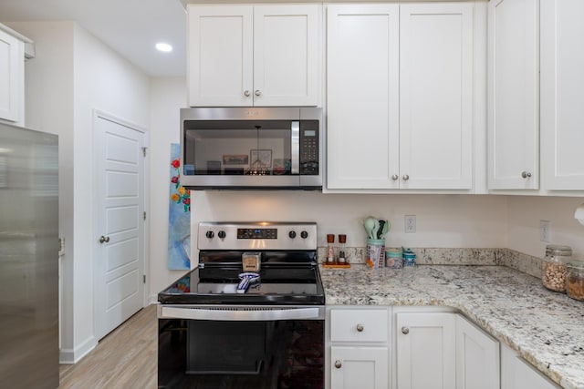 kitchen featuring appliances with stainless steel finishes, white cabinets, light stone counters, and light hardwood / wood-style floors