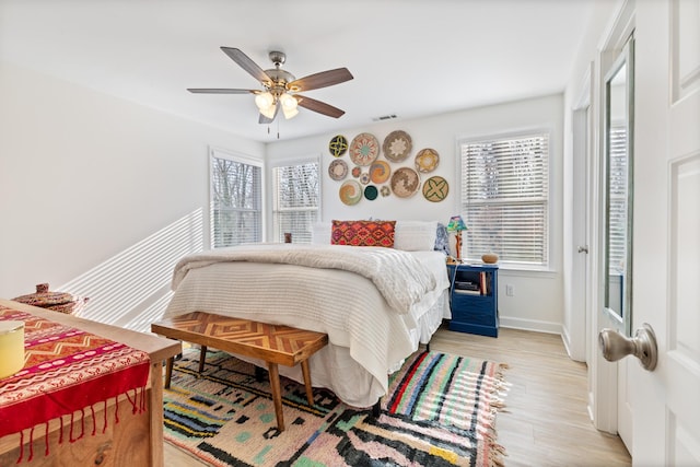 bedroom with multiple windows, ceiling fan, and light wood-type flooring