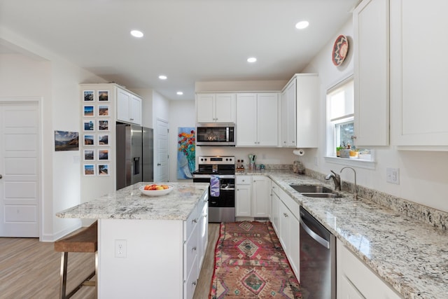 kitchen featuring stainless steel appliances, a center island, sink, and white cabinets