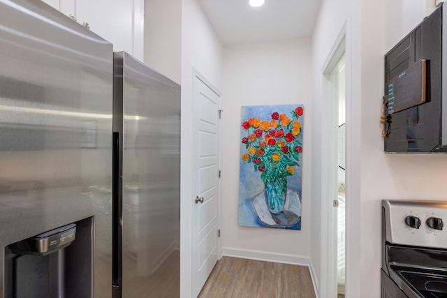 kitchen featuring white cabinetry, stainless steel fridge, electric range, and light hardwood / wood-style flooring