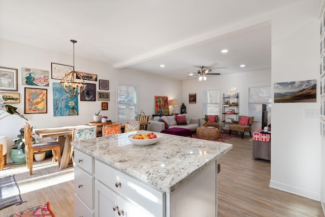 kitchen with hanging light fixtures, a center island, white cabinets, and light wood-type flooring