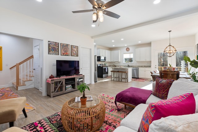 living room featuring sink, ceiling fan with notable chandelier, and light hardwood / wood-style flooring