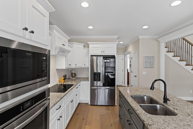 kitchen featuring sink, crown molding, stainless steel appliances, light stone counters, and white cabinets