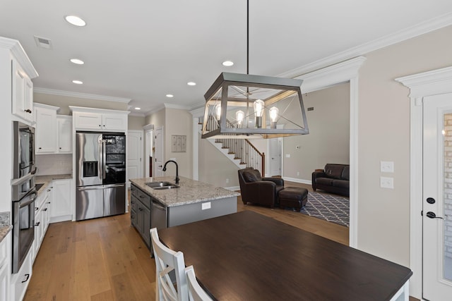 kitchen featuring light stone counters, appliances with stainless steel finishes, a kitchen island with sink, and white cabinets