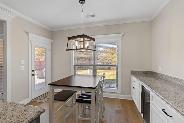 dining space with white cabinetry, hanging light fixtures, light hardwood / wood-style flooring, and light stone countertops