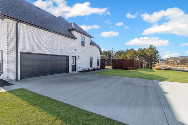 view of side of property featuring a garage and a lawn