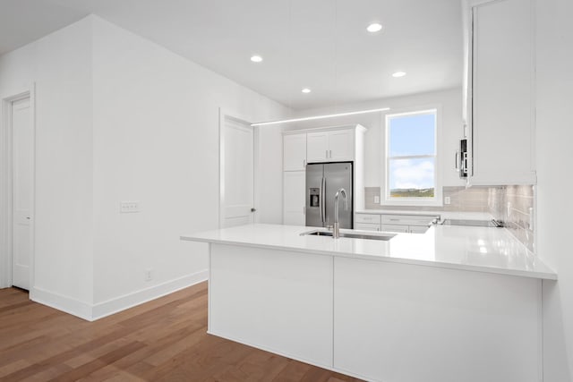 kitchen with sink, stainless steel appliances, white cabinets, decorative backsplash, and kitchen peninsula