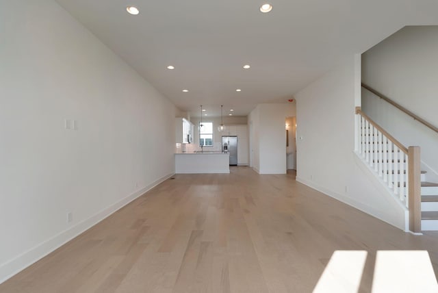 unfurnished living room featuring sink and light hardwood / wood-style flooring