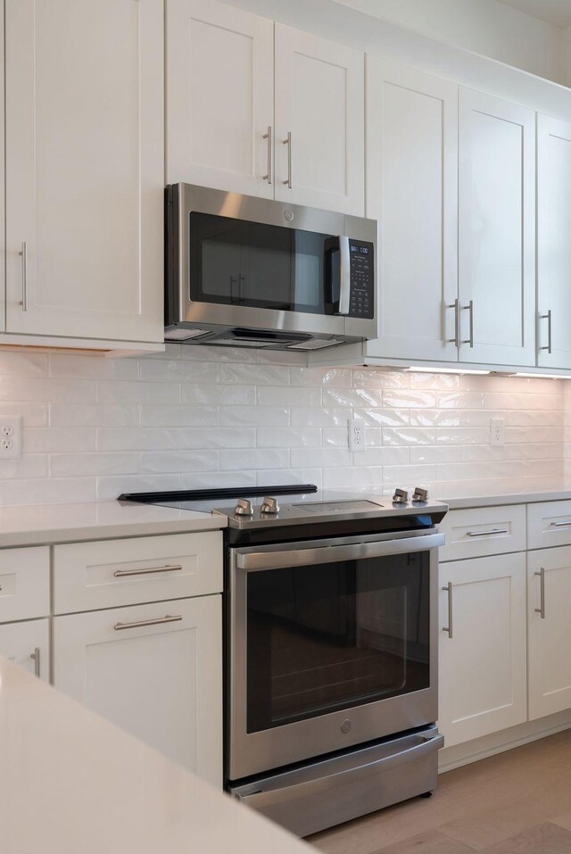 kitchen with decorative backsplash, stainless steel appliances, and white cabinets