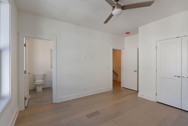 unfurnished bedroom featuring ensuite bathroom, a closet, ceiling fan, and light hardwood / wood-style flooring