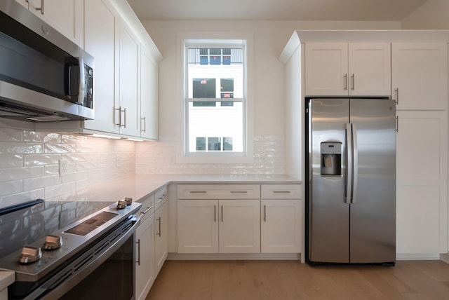 kitchen with stainless steel appliances, light wood-type flooring, white cabinets, and backsplash