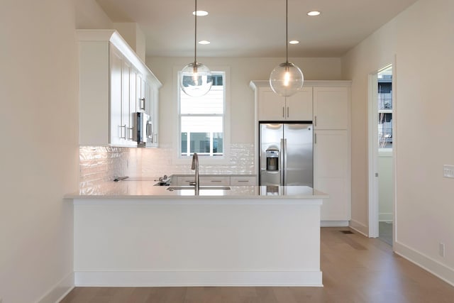 kitchen featuring tasteful backsplash, sink, white cabinets, hanging light fixtures, and stainless steel appliances