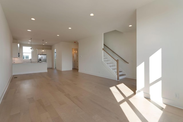 unfurnished living room with sink and light wood-type flooring