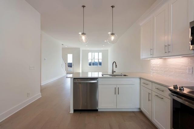 kitchen with sink, white cabinetry, tasteful backsplash, appliances with stainless steel finishes, and kitchen peninsula