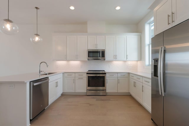 kitchen with sink, hanging light fixtures, white cabinets, and appliances with stainless steel finishes