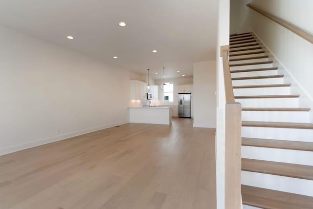 unfurnished living room with sink and light hardwood / wood-style flooring