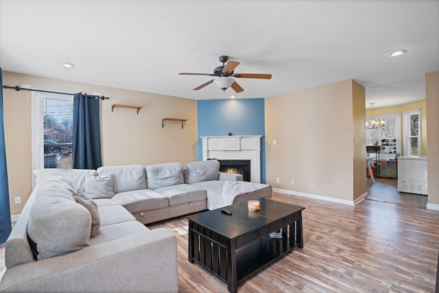 living room featuring ceiling fan with notable chandelier and hardwood / wood-style floors