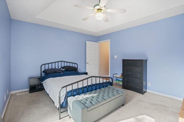 carpeted bedroom with ceiling fan and a tray ceiling