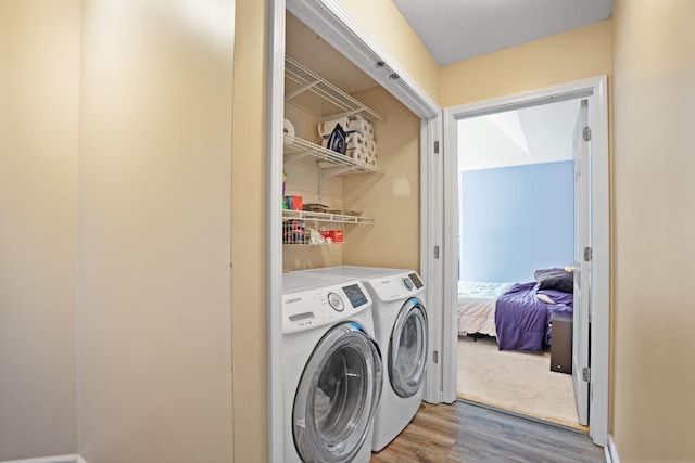 clothes washing area with light hardwood / wood-style floors and washing machine and dryer