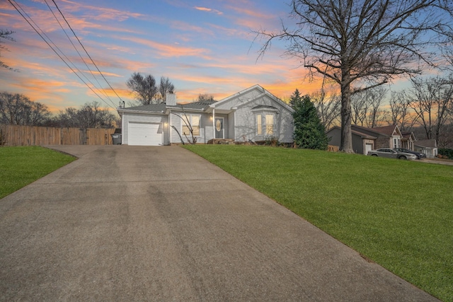 single story home featuring a garage and a lawn