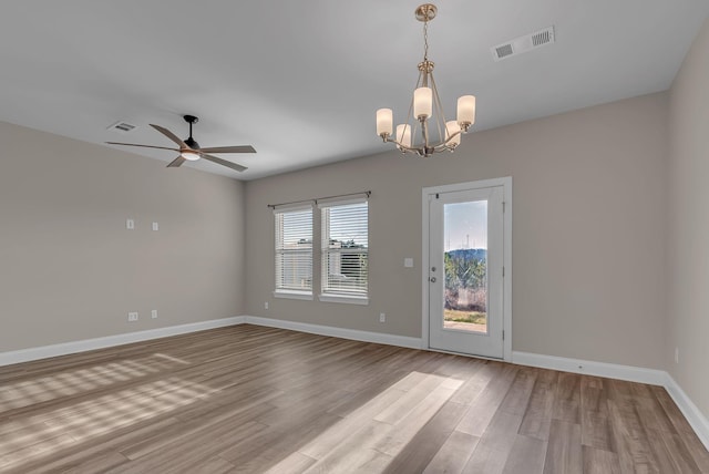 empty room with ceiling fan with notable chandelier and light hardwood / wood-style floors