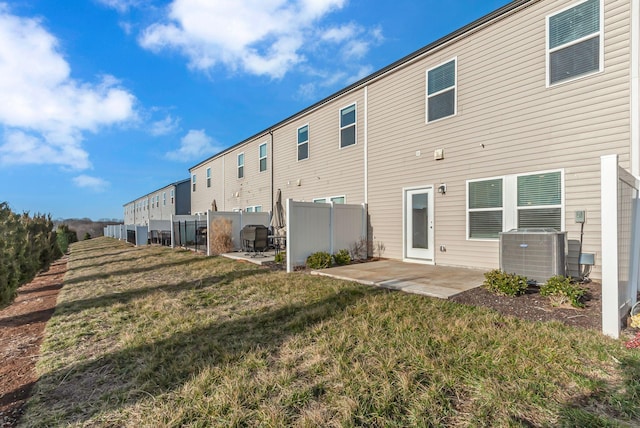 back of property with central AC unit, a yard, and a patio