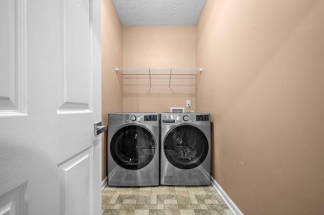 clothes washing area featuring washing machine and dryer and a textured ceiling