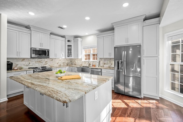 kitchen with stainless steel appliances, a kitchen island, sink, and dark hardwood / wood-style flooring