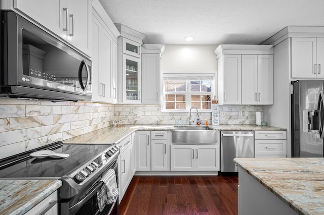 kitchen featuring white cabinetry, sink, light stone counters, and stainless steel appliances