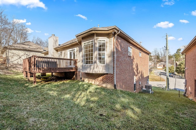 rear view of house with central AC unit, a yard, and a deck