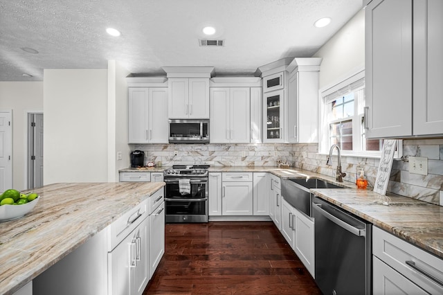 kitchen with sink, white cabinetry, tasteful backsplash, appliances with stainless steel finishes, and light stone countertops