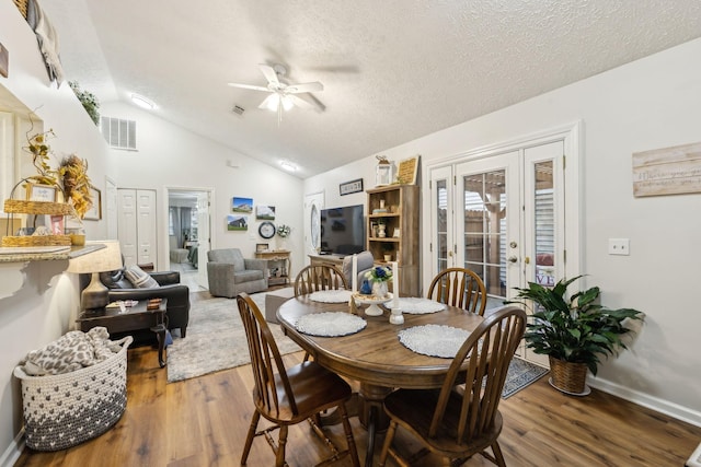 dining room featuring lofted ceiling, ceiling fan, a textured ceiling, dark hardwood / wood-style flooring, and french doors