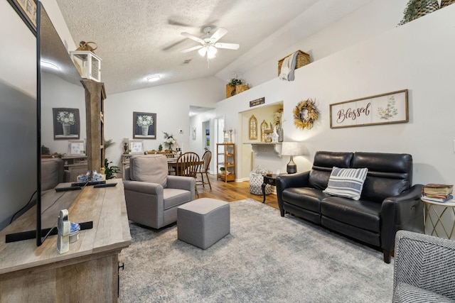 living room with wood-type flooring, lofted ceiling, a textured ceiling, and ceiling fan