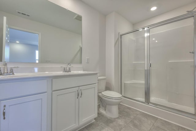 bathroom featuring vanity, a shower with shower door, and toilet