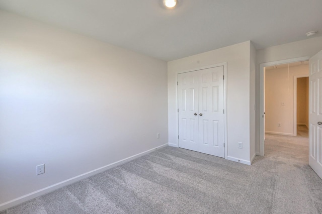 unfurnished bedroom featuring light carpet and a closet