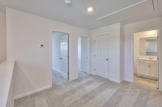 unfurnished bedroom featuring connected bathroom, sink, and light carpet