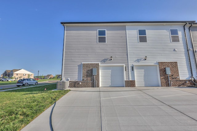 view of side of home featuring central AC, a garage, and a yard