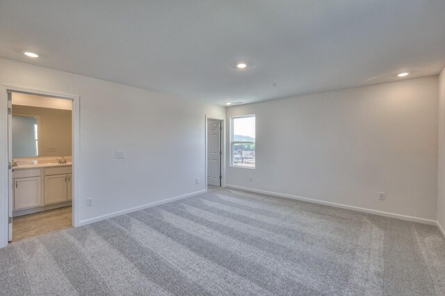 spare room featuring sink and light carpet