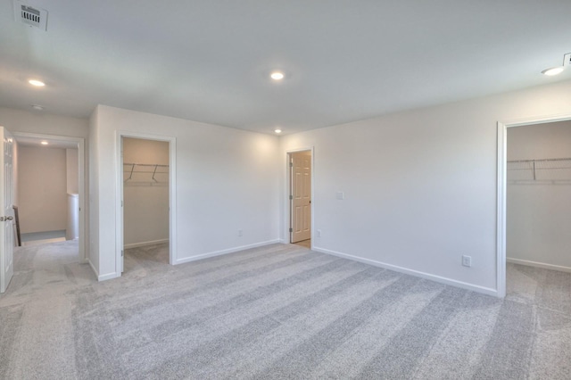 unfurnished bedroom with light carpet, a spacious closet, and a closet