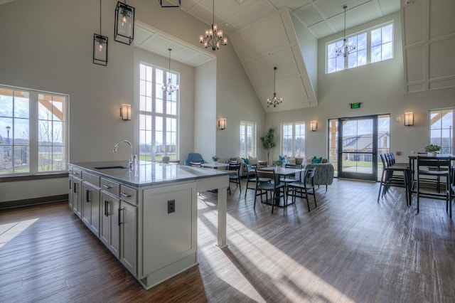 kitchen with sink, plenty of natural light, dark wood-type flooring, a center island with sink, and an inviting chandelier